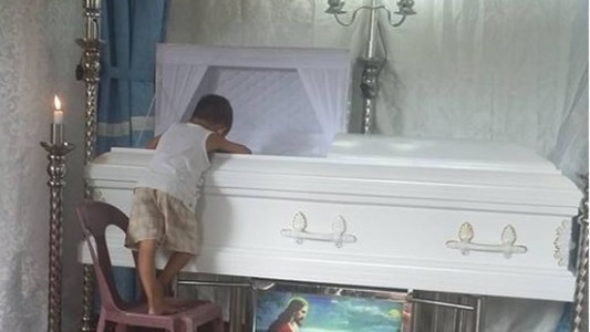 La foto conmovedora del nene que no quiere separarse del ataúd de su madre
