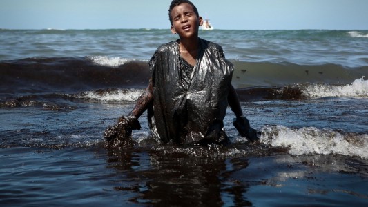 El nene que sale del mar embadurnado en petróleo tras un derrame: la foto que conmueve al mundo