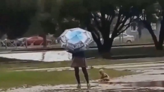 Niño se baña desnudo en un charco mientras su madre se protege de la lluvia