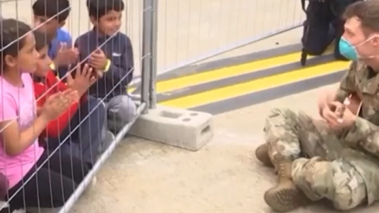 Un soldado entretiene con un ukelele a niños afganos evacuados